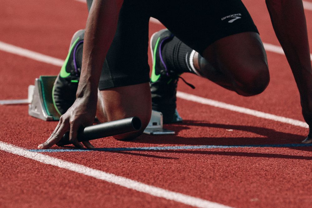Runner with his knees on the floor preparing for a relay race