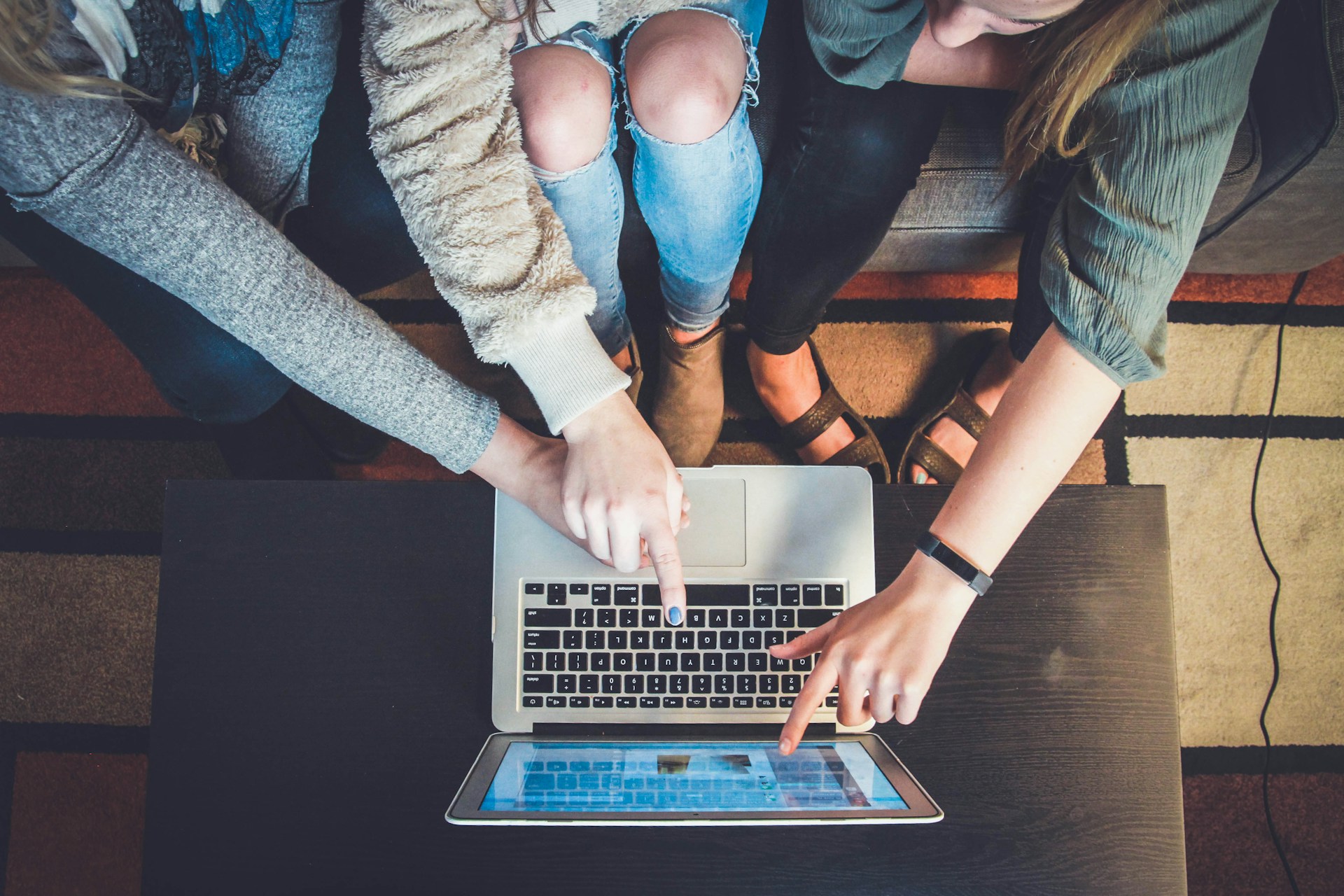 Group of people pointing something on a laptop screen